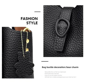Detail view of black pebbled leather texture with bear charm and buckle decoration