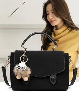 Detail of black matte messenger bag with OBZUNO embossed logo and cute plush monster charm