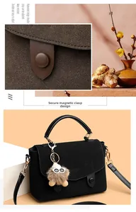 Close-up of black matte messenger bag with adjustable strap and cute monster charm