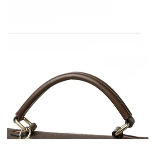 Detailed close-up of dark brown handbag handle with neat stitching and gold D-ring