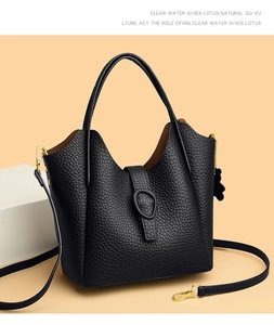 Macro detail of black litchi grain leather texture and gold hardware on bucket bag