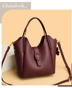 Macro view of burgundy lychee grain leather texture and gold hardware on bucket bag