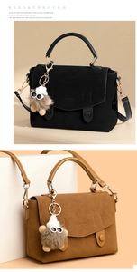 Detail of suede crossbody bag with metal buckles, leather handle and plush charm