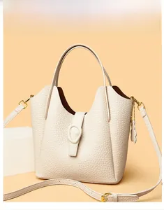 Detail view of cream lychee texture leather bucket bag with gold hardware and chain strap