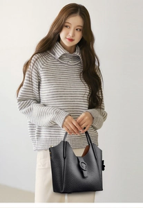 Close-up of black lychee grain leather bucket bag with decorative buckle and top handle