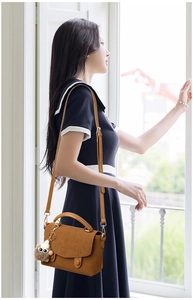 Brown vintage messenger bag with top handle and owl plush charm shown on a model