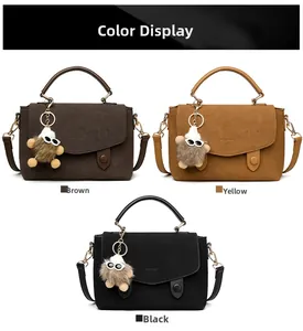 Three large crossbody messenger bags in brown, yellow, and black with plush charms