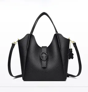 Front view of black pebble leather bucket bag with oval buckle and bear charm