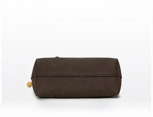 Detail view of the flat rectangular base and stitching of a dark brown suede messenger bag