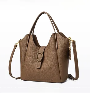 Detail of yellow-brown bucket bag in pebble grain leather with golden metal hardware