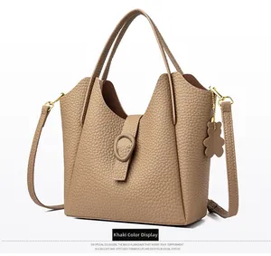 Detail view of khaki pebbled leather bucket bag with gold hardware and bear charm