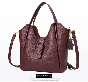 Detail of burgundy lychee leather bucket bag with gold hardware and bear charm