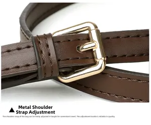 Detail of adjustable brown leather shoulder strap with polished gold buckle and fine stitching