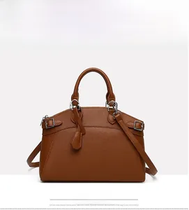 Detail view of brown lychee textured leather tote with metal buckle and shoulder strap