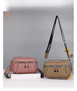 Detail view of pink and khaki crossbody bags with lychee grain leather and multi-zip pockets