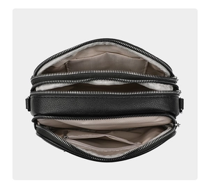 Detailed top view of a black crossbody bag showing three zippered compartments and lining