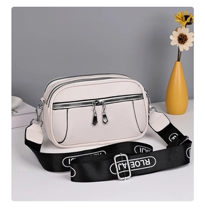 Macro detail of creamy white faux leather texture and multi-layer zippers on crossbody bag