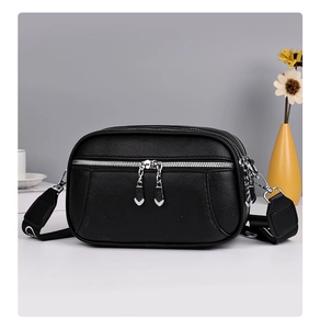 Detailed macro view of black lychee leather crossbody bag with three silver heart zippers