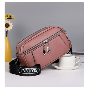 Detail of soft faux leather crossbody bag with triple zippers and wide logo strap