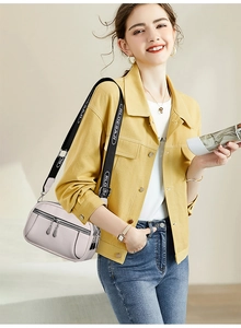 Detail of light grey multi-pocket crossbody bag with logo strap and metal zippers