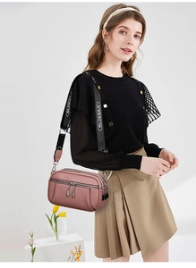 Detail of soft faux leather crossbody bag in dusty pink with triple zipper layers