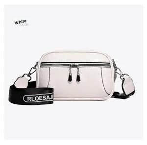 Detailed macro view of white pebble grain leather crossbody bag with dual metal zippers
