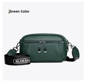Detail view of green soft leather crossbody bag with heart zippers and striped strap