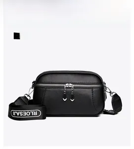 Detail of black pebbled leather crossbody bag with double zippers and logo webbed strap