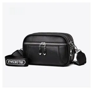 Detail of black pebbled leather crossbody bag with multi-layer zippers and wide strap