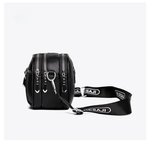 Side view of black pebble leather crossbody bag with triple zippers and wide textile strap