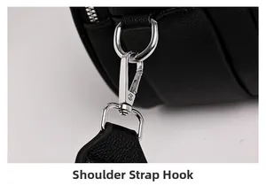 Detail of silver metal shoulder strap hook on black pebbled leather crossbody bag