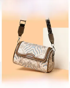 Detail of vintage embroidery fabric and brown leather on this stylish cylindrical bag