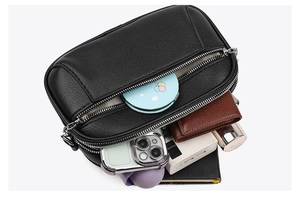 Multi-compartment crossbody bag in black pebble leather showing ample storage capacity