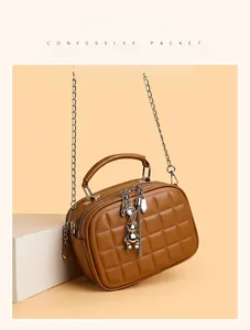 Detail of brown quilted crossbody bag with silver chain strap and bear charm pendant