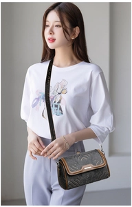 Grey textured crossbody bag with brown trim and wide 'Have a Nice Day' branded strap