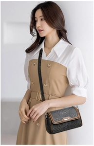Detail of grey textured flap bag with brown leather piping and embroidered wide strap