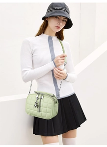 Detail of mint green quilted crossbody bag with metal chain strap and bear pendant charm