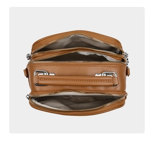 Internal view of brown crossbody bag showing three zipper compartments and striped lining