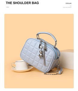 Close-up of light blue quilted box bag with silver bear charm and chain strap
