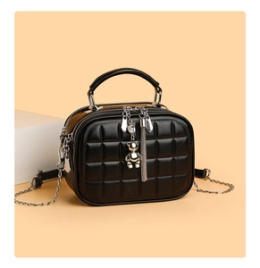Detail of black quilted crossbody bag with silver bear charm and tassel decoration