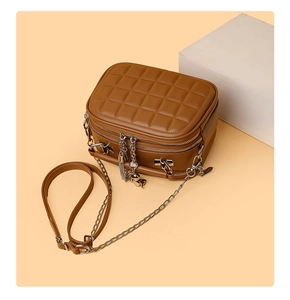 Detail view of caramel quilted crossbody bag with dual silver zippers and fringe tassel