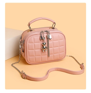 Detail of pink quilted leather bag with bear charm and dual zipper compartments