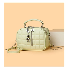 Detail of mint green quilted crossbody bag with dual zippers and cute bear charm