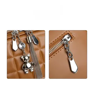 Detailed macro view of brown quilted leather bag with silver charms and metal zipper