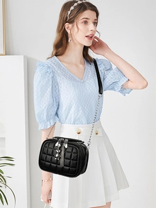 Close-up of black quilted chain bag with silver bear charm and fringe detail