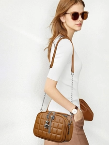 Detailed side view of brown quilted crossbody bag with chain strap and bear charm