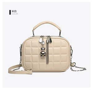 Detail of cream quilted handbag with silver chain strap and decorative bear charm