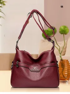 Detail of burgundy PU leather shoulder bag with lychee texture and metallic logo plaque