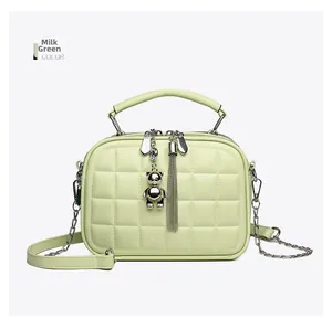 Detail of milk green quilted handbag with silver bear pendant and chain strap