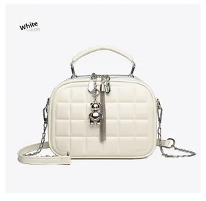 Detail of off-white quilted handbag with silver chain and metal bear charm
